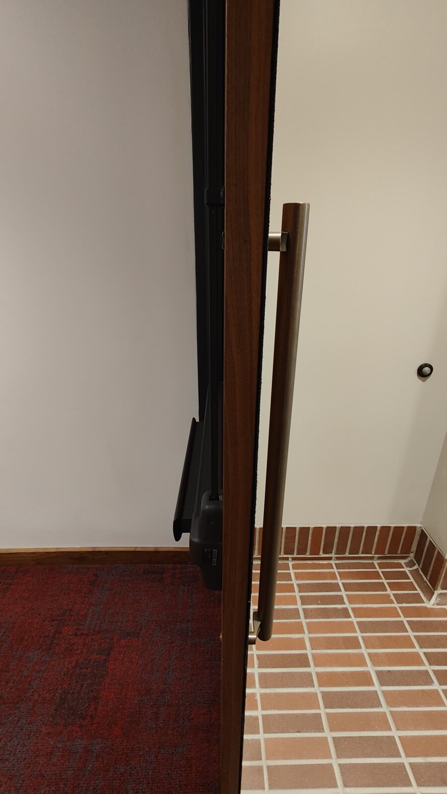 View of entrance door to the auditorium with tiled floor at exterior and loop low/flat carpet inside auditorium.