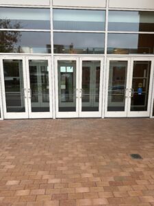 The right-most door is the one that is triggered by the automatic door opener. Both doors (internal and external) open at the same time with the push of the automatic door button so there is no delay. 